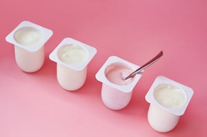 Four yogurt containers on a pink background